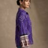 Side view of a woman wearing a purple printed shirt with full sleeves and ethnic border cuff detailing.