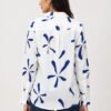Back view of a women's white printed shirt featuring abstract navy blue and blush pink floral motifs, full sleeves, curved hem, and a relaxed fit paired with dark blue denim jeans.