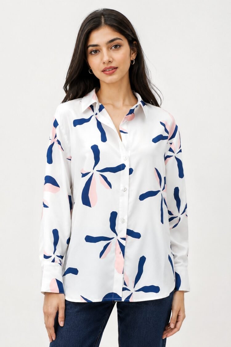 Women's white printed shirt featuring abstract navy blue and blush pink floral motifs, full sleeves, button-down front, and a relaxed fit, styled with dark blue denim jeans.
