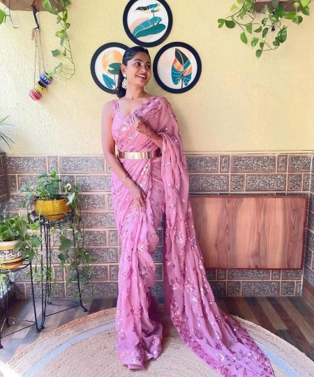 A model showcasing a beautiful light pink ready-to-wear designer Indian saree with intricate sequence work, perfect for any occasion.